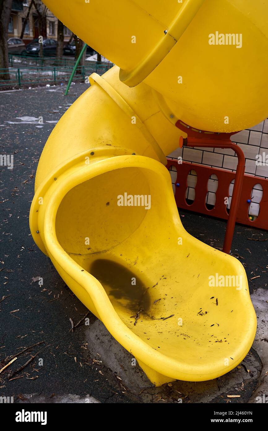 Große gelbe Rutsche auf dem Spielplatz im Hof sammelt viel schmutziges Wasser nach Regen und Kinder können es nicht benutzen und nach unten rutschen Stockfoto