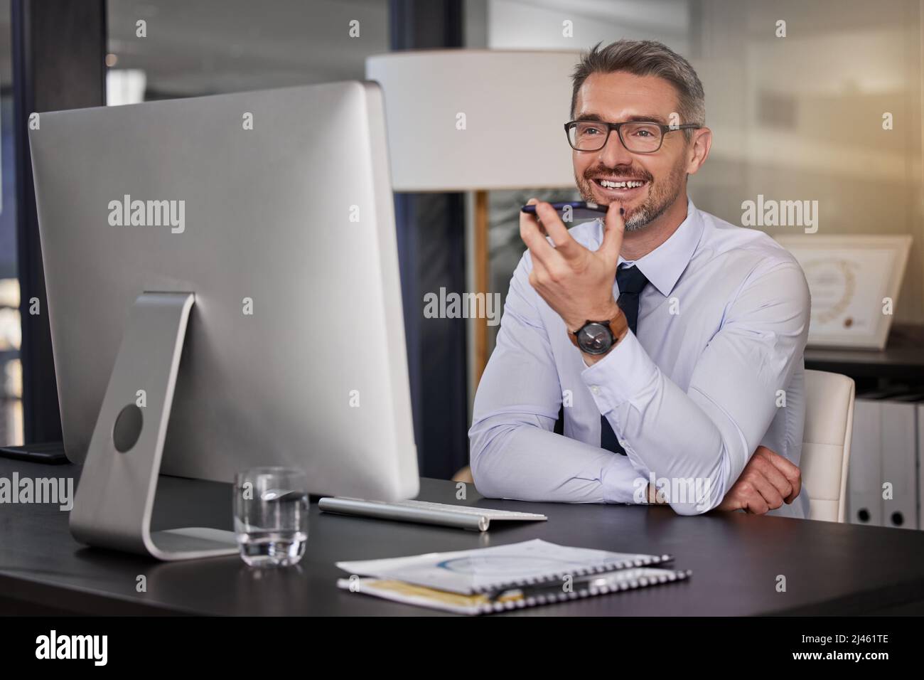 Ich gehe Sie Schritt für Schritt durch den Prozess. Aufnahme eines Geschäftsmannes, der sein Mobiltelefon benutzte, während er an seinem Schreibtisch saß. Stockfoto