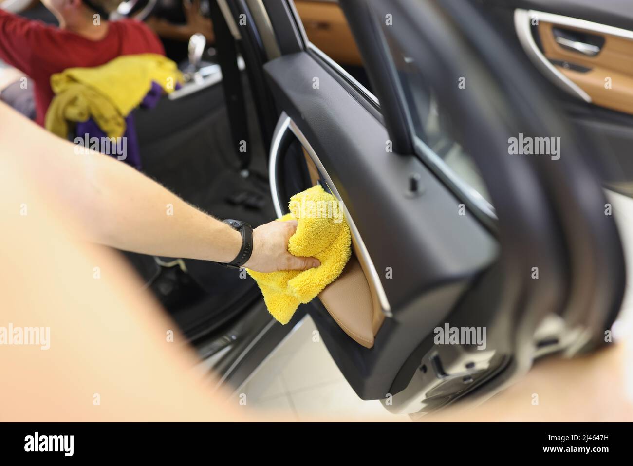 Autoreiniger, der die Türverkleidung des Fahrzeugs mit einem Mikrofasertuch reinigt Stockfoto