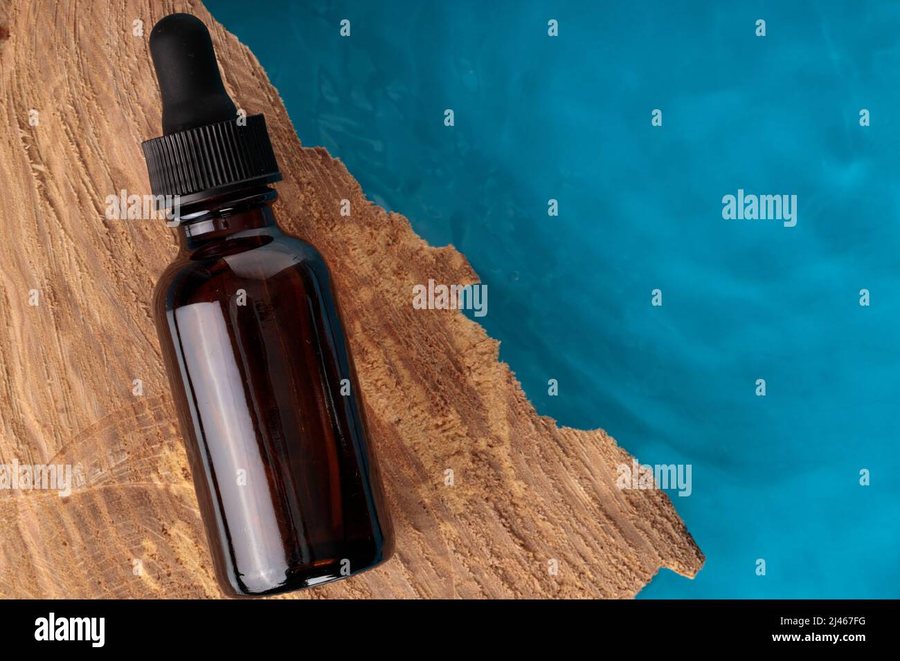 Kosmetikflasche mit Brandstiftung, Top Shot. Braune Flasche auf Holz, blaues Wasser. Platz für Text. Stockfoto