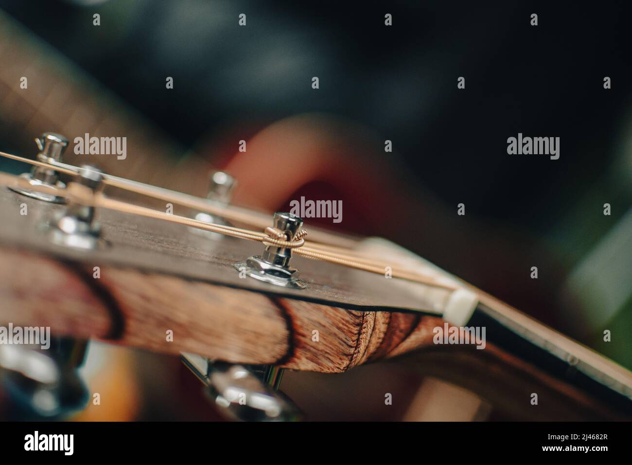 Eine Nahaufnahme des Kopfstocks einer akustischen Gitarre, die den Ankerwinde mit einer Bronzesaite zeigt. Stockfoto
