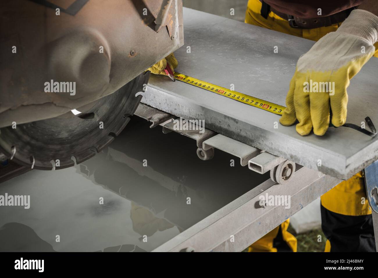 Arbeiter mit Maßband Messen und schneiden Betonblöcke auf Größe mit leistungsstarken Kreissäge. Industriedesign. Stockfoto