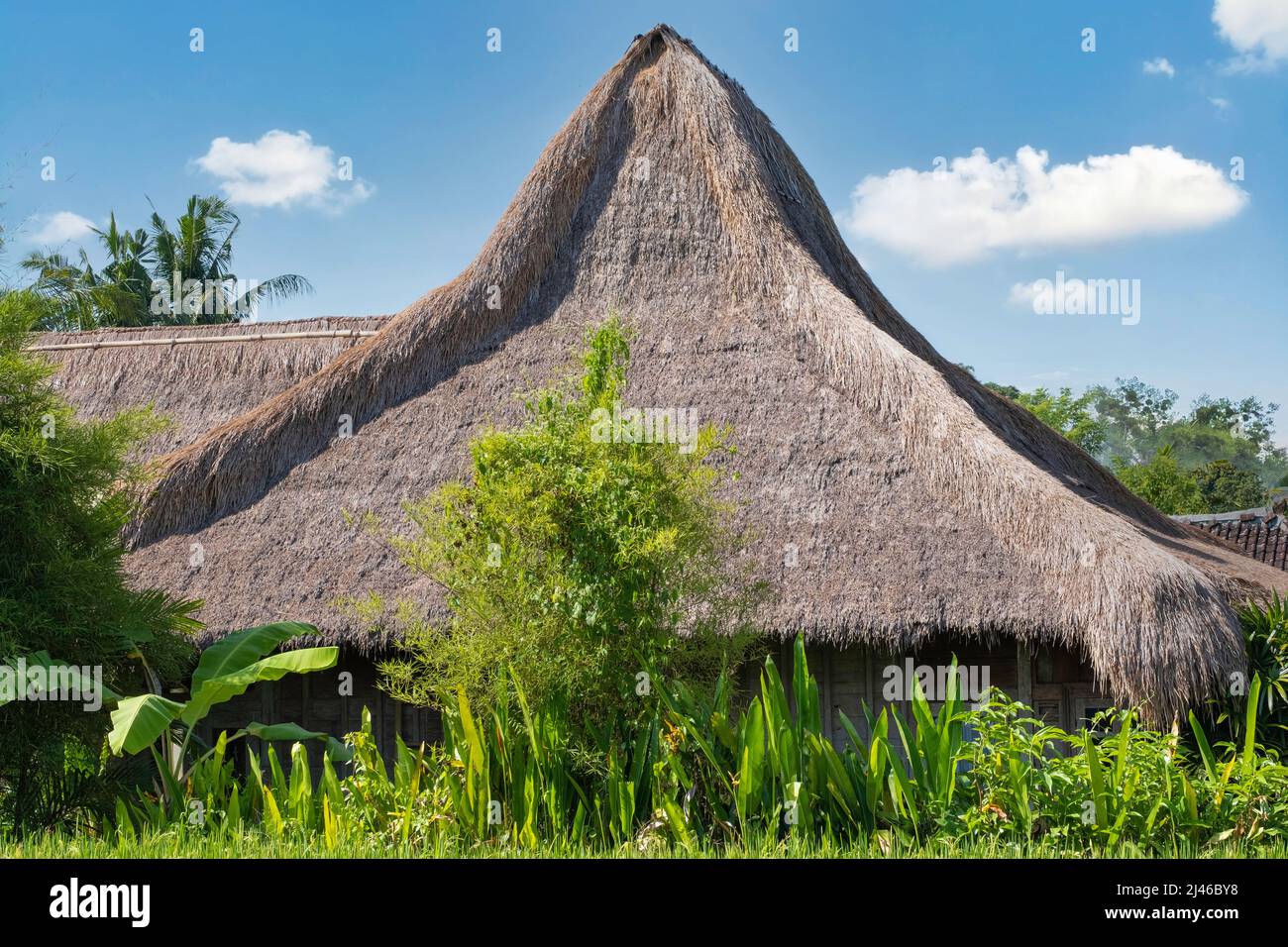 Indonesische Hütte mit Strohdach, aus Bambusstrohhalmen und Stäben. Blauer Himmel und Wolken Hintergrund Stockfoto