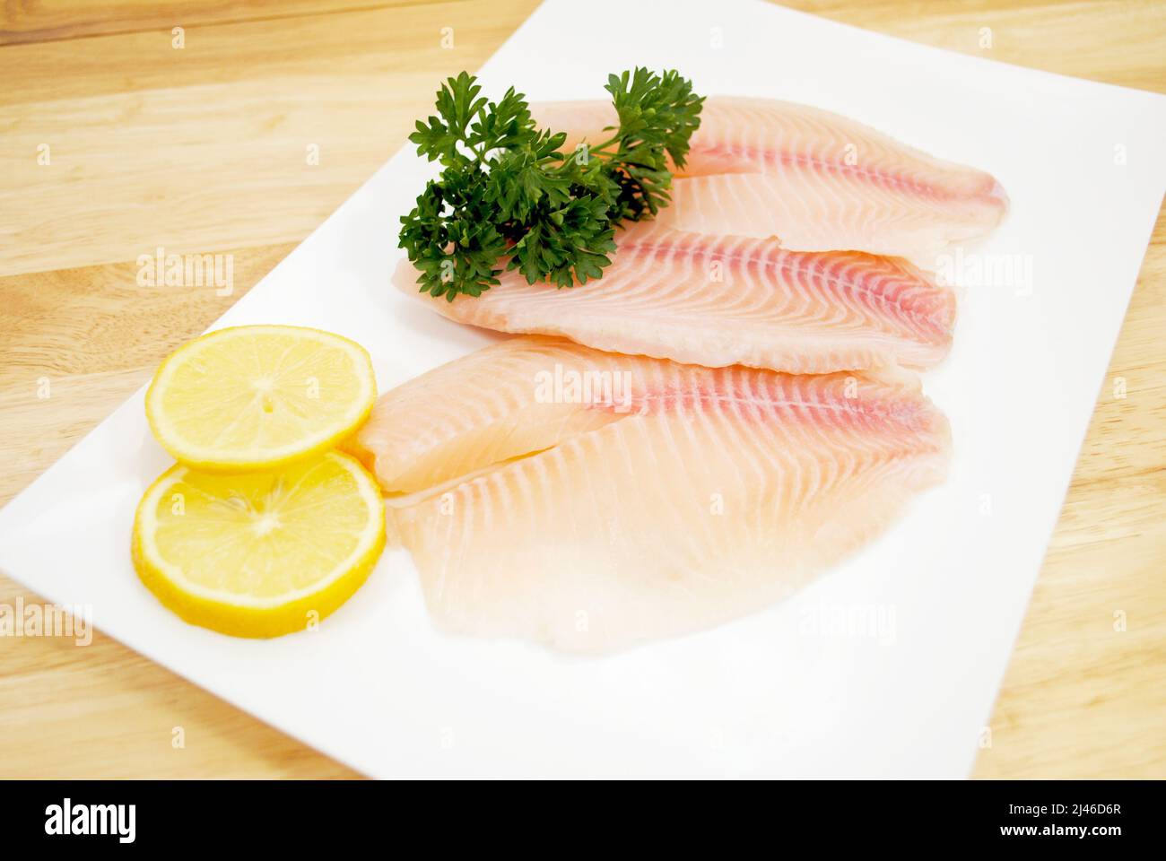 Bio-Weißfisch garniert mit Zitrone und Petersilie Stockfoto