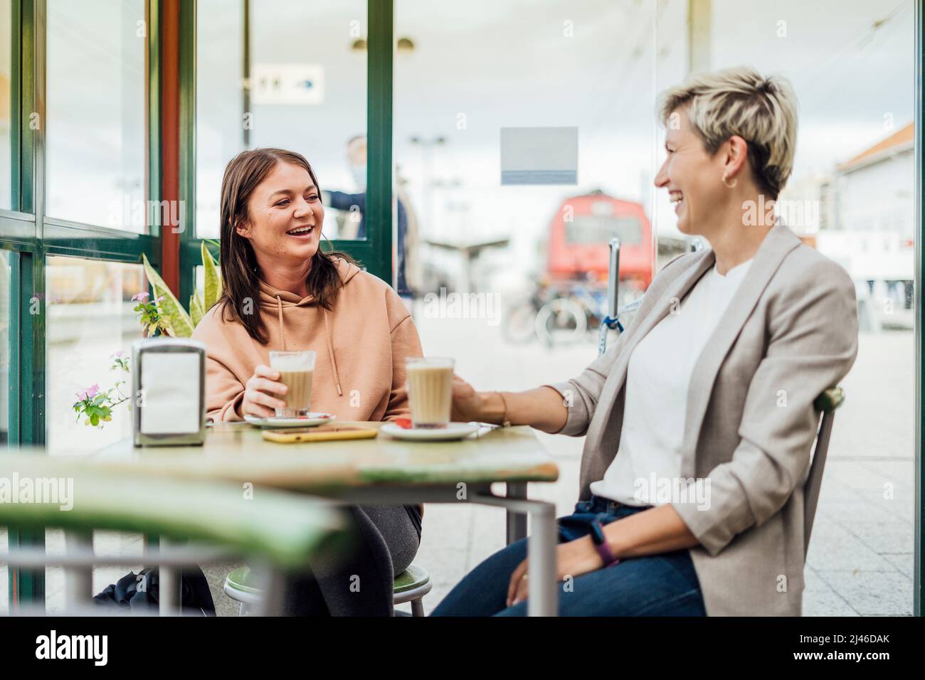 Zwei Freundinnen trinken Kaffee und genießen Zeit im Café am Bahnhof Stockfoto