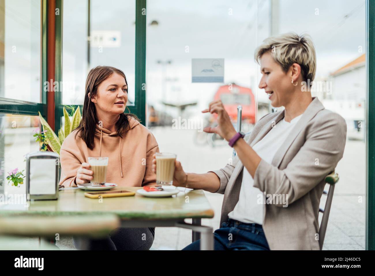 Zwei Freundinnen trinken Kaffee und genießen Zeit im Café am Bahnhof Stockfoto