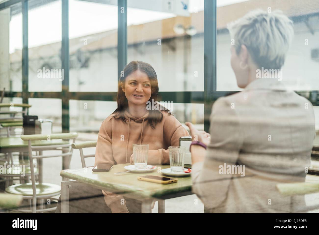 Zwei Freundinnen trinken Kaffee und genießen Zeit im Café am Bahnhof Stockfoto