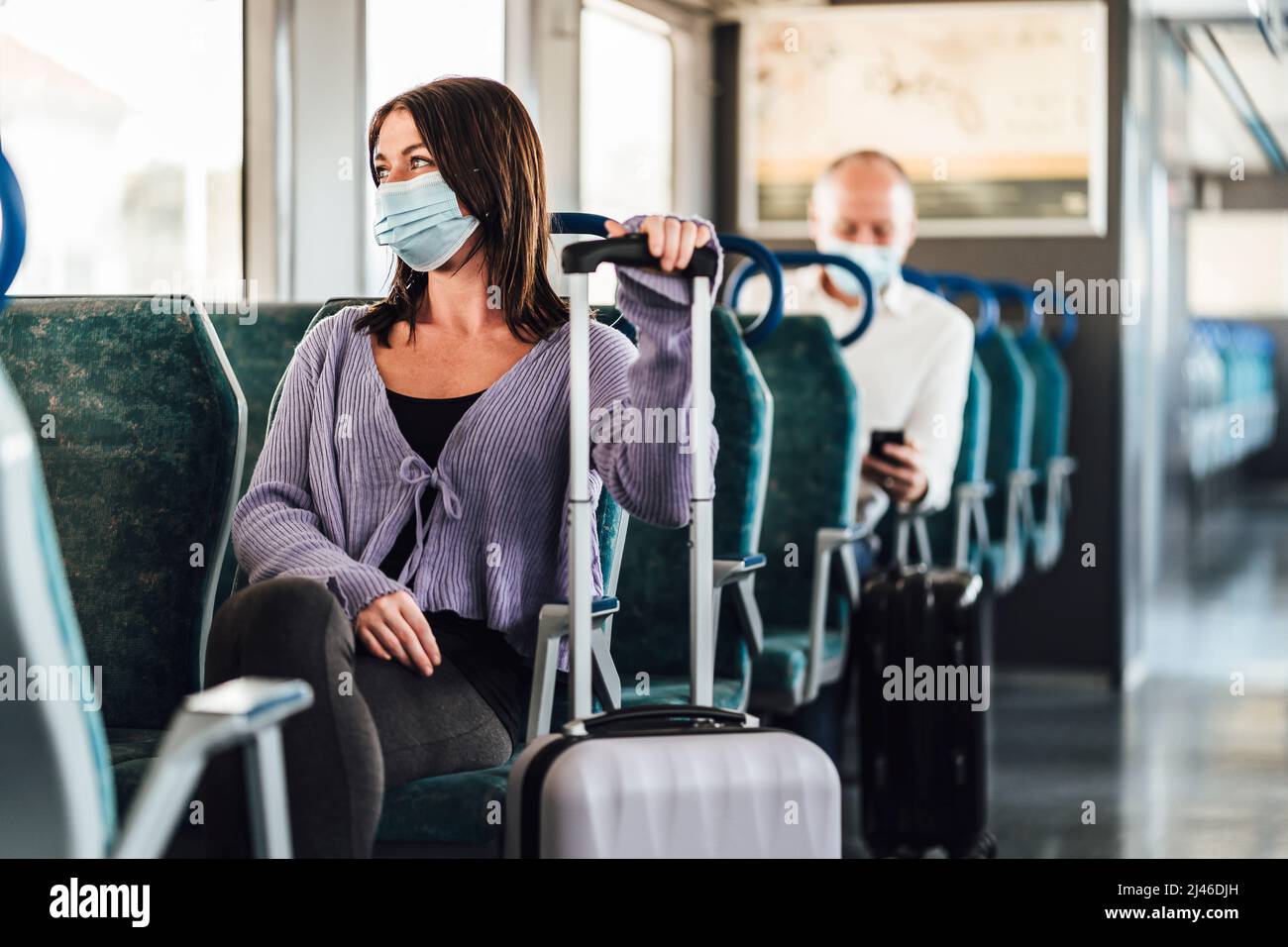 Ernsthafte Passagiere in Schutzmasken während ihrer Zugfahrt Stockfoto
