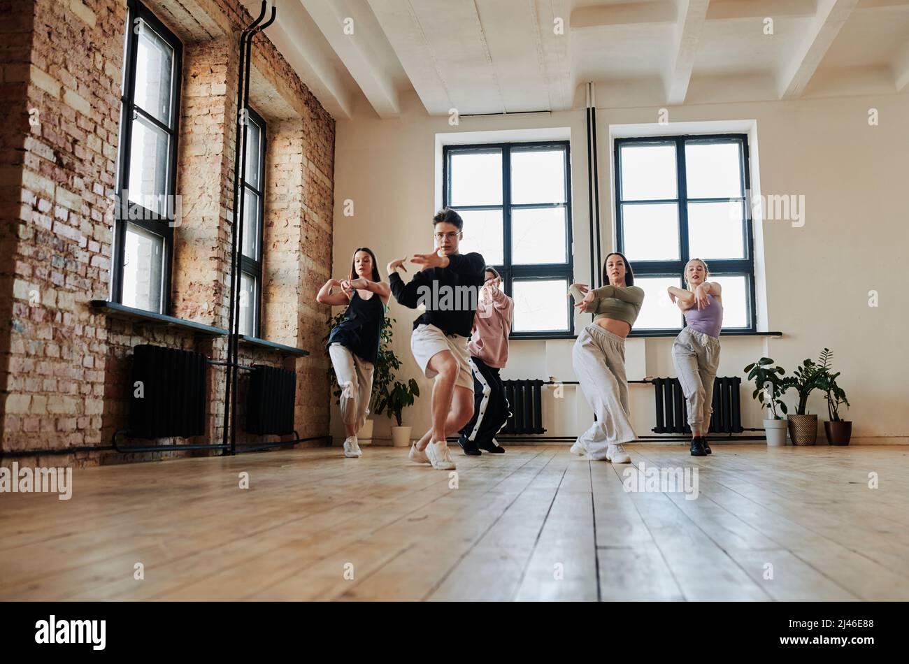 Gruppe von energischen Teenagern in aktiven Ohren, die nach ihrem Leiter des Performance-Teams im Studio die Mode der Tanzübung wiederholen Stockfoto