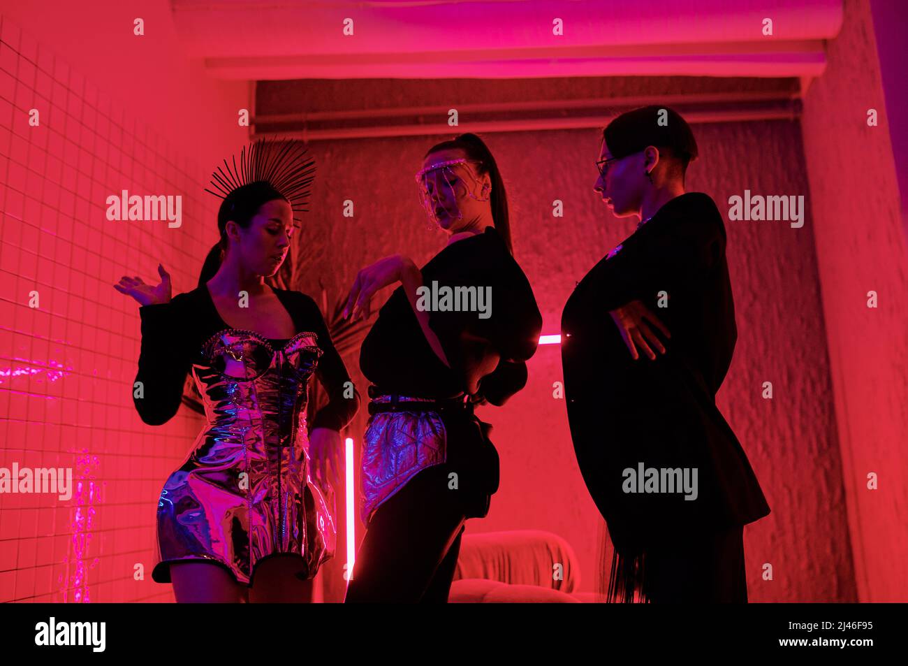 Drei Jugendliche Performer in noblem Gewand, die im modernen Nachtclub modischen Tanz vorführen, während sie vor der Kamera stehen Stockfoto