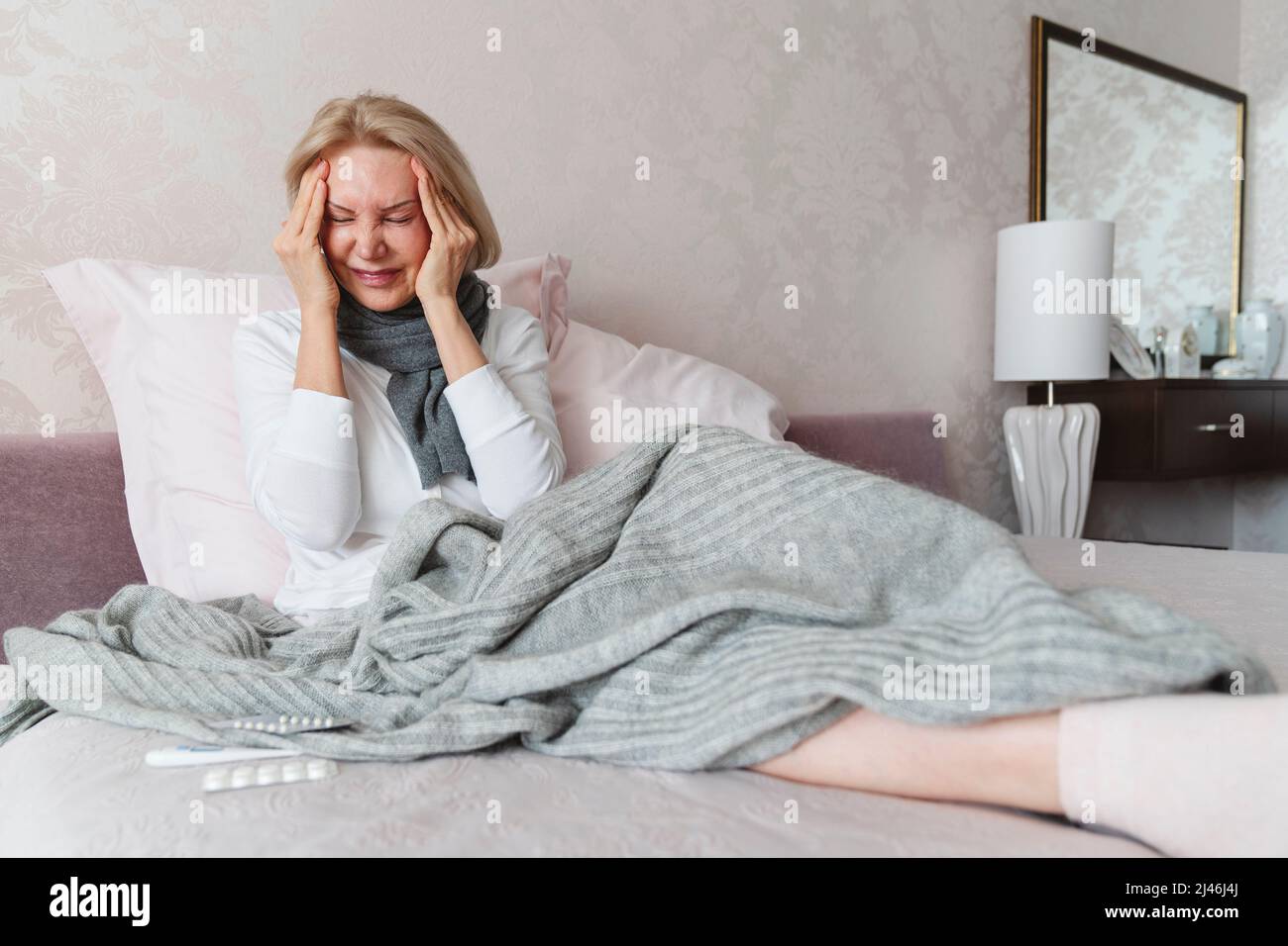 Eine Frau leidet zu Hause im Bett an einer Krankheit. Stockfoto