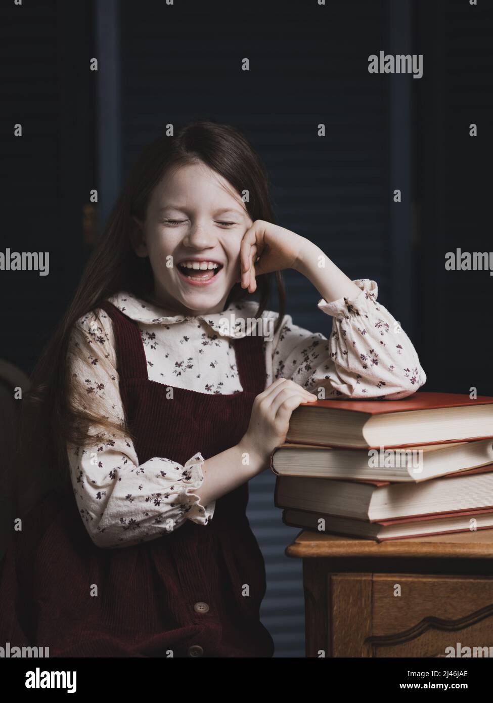 Porträt eines glücklichen Mädchens am Tisch mit Büchern. Stockfoto