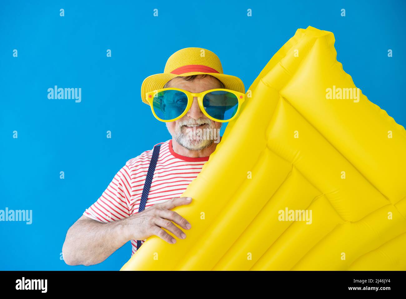 Glücklicher älterer Mann, bereit zu reisen. Person mit gelber Luftmatratze. Sommerurlaub und Urlaubskonzept Stockfoto