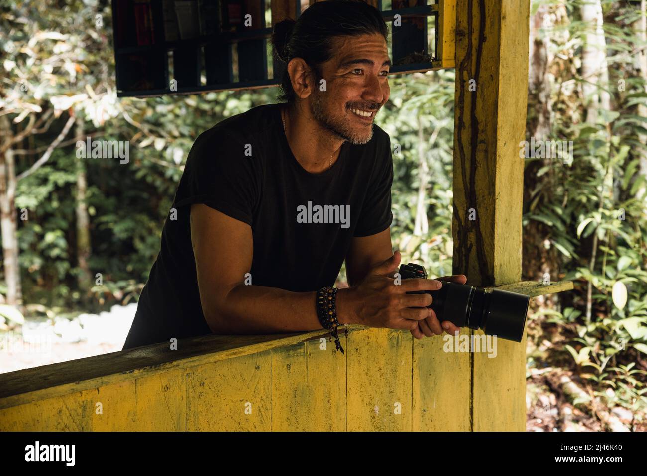 Mann lächelt mit seiner Kamera auf dem Wald Stockfoto