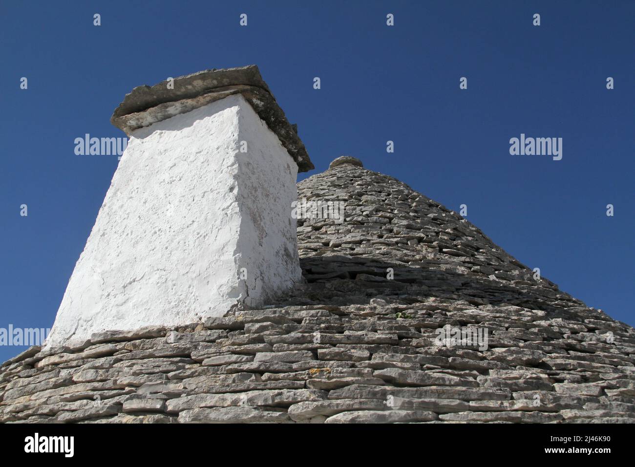 Das Kegeldach mit Kamin eines 500 Jahre alten traditionellen Trullo-Felshauses in Alberobello, Italien. Stockfoto