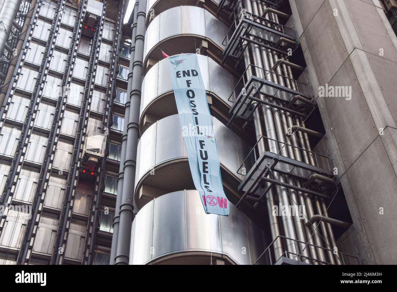 London, Großbritannien. 12.. April 2022. Das Banner „End Fossil Fuels Now“ hängt an der Seite des Lloyd's Building. Extinction Rebellion-Aktivisten verursachten Chaos beim Versicherungsgiganten Lloyd’s in der City of London und forderten, dass das Unternehmen die Versicherung von Projekten mit fossilen Brennstoffen einstellt. Einige Demonstranten kletterten auf das Gebäude und ließen Transparente fallen, während andere sich um das Gebäude herum klebten und verketteten. Kredit: Vuk Valcic/Alamy Live Nachrichten Stockfoto