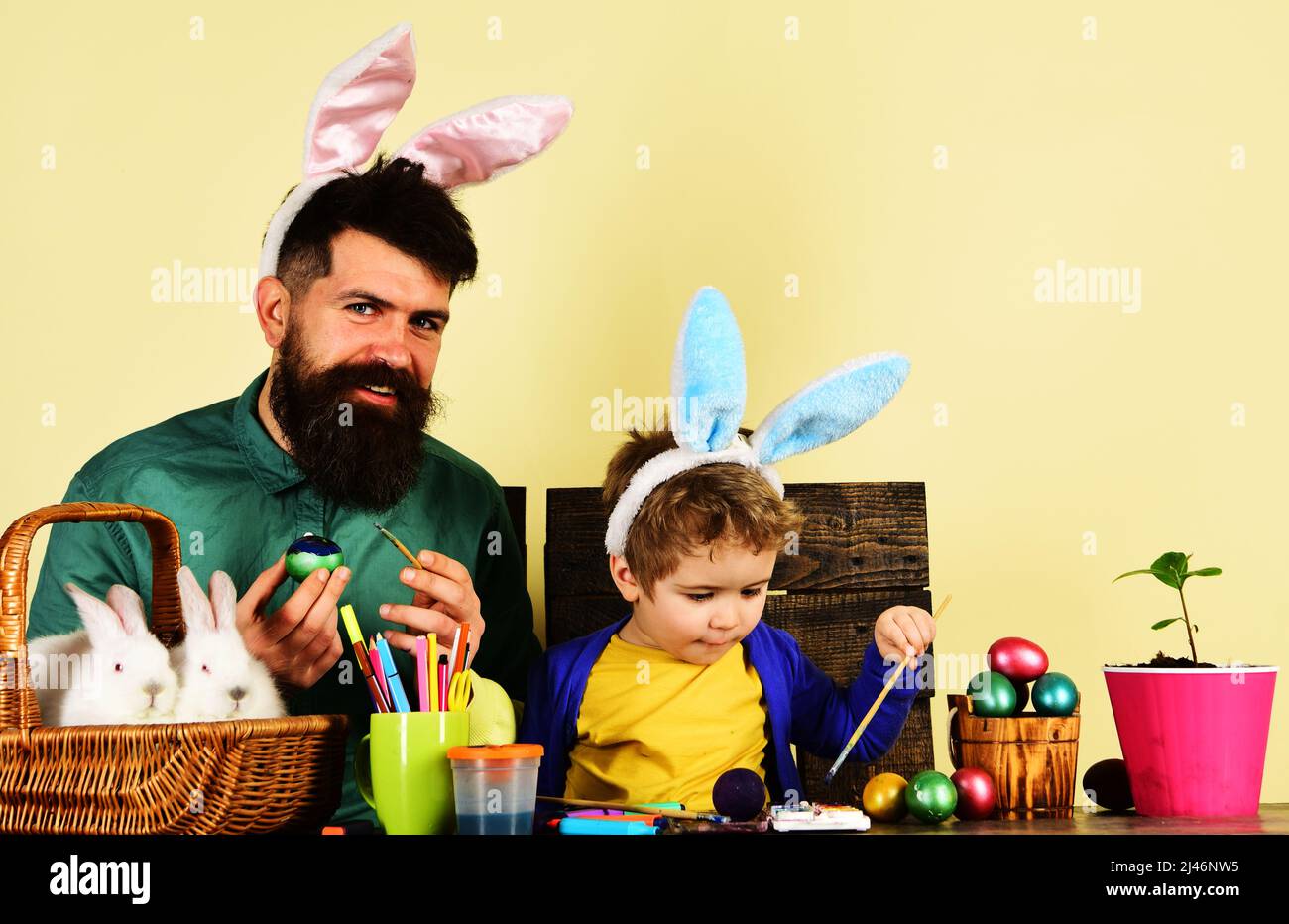 Vater und Sohn malen Eier. Kaninchen Familie in Hasen Ohren. Ideen zum Dekorieren von Eiern. Ostertradition. Stockfoto
