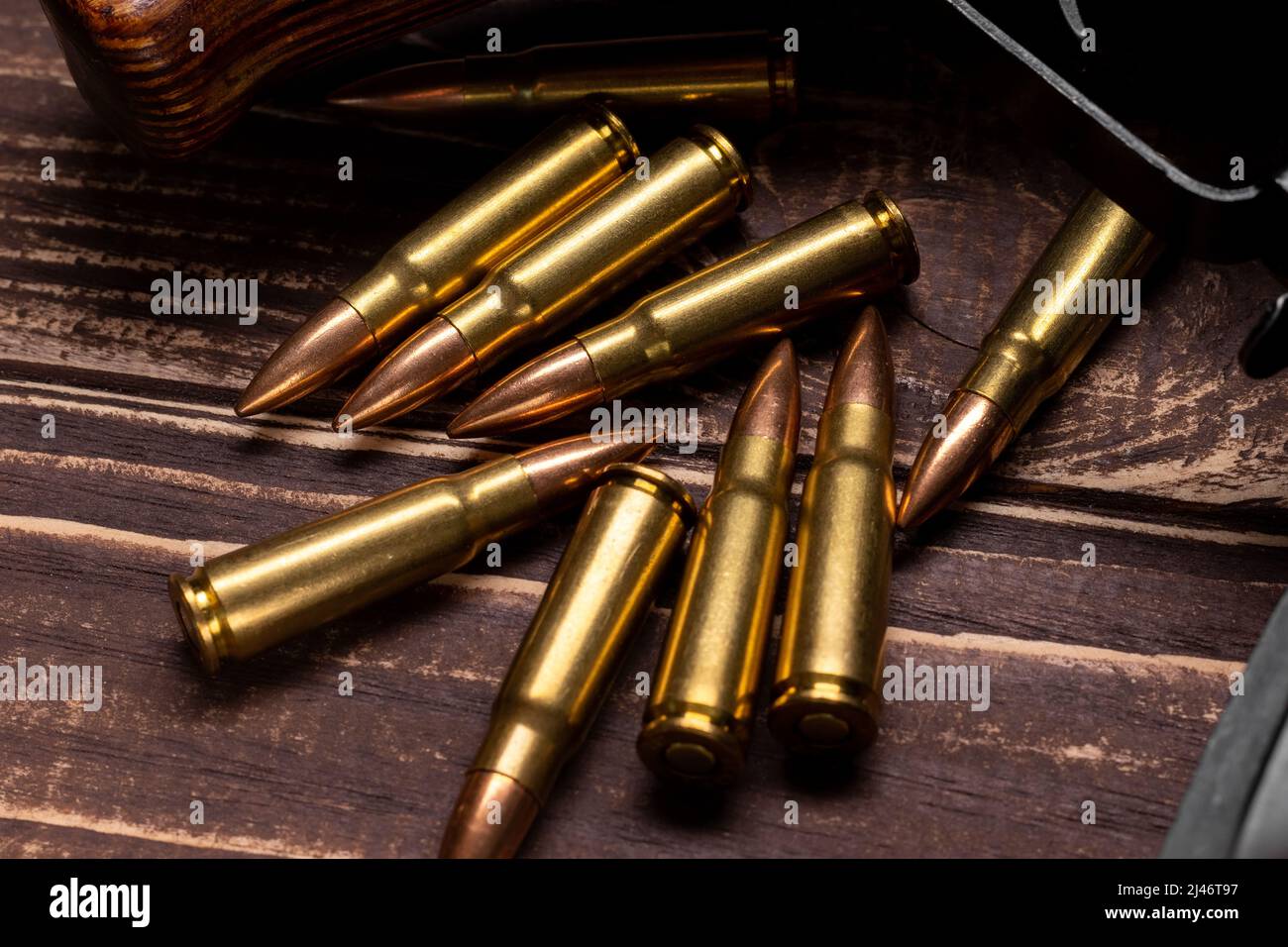 Kugeln und Kalaschnikow-Sturmgewehr auf Holzgrund. Kartuschen im Kaliber 7,62 für ak 47 Nahaufnahme. Selektiver Fokus Stockfoto