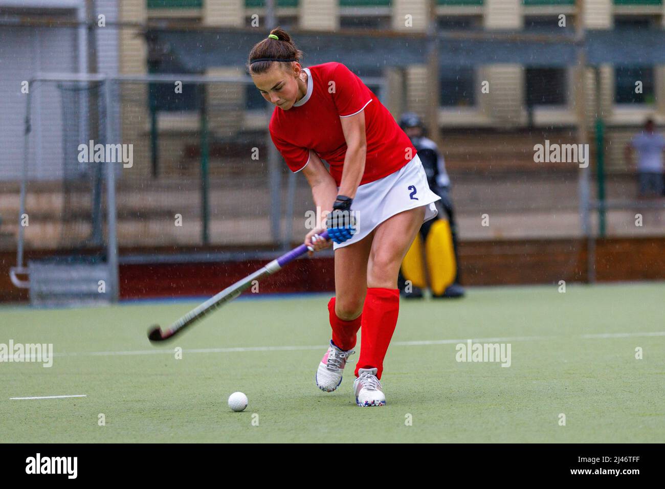 Teenager-Mädchen schlagen den Ball während Hockey-Spiel unter starkem Regen Stockfoto