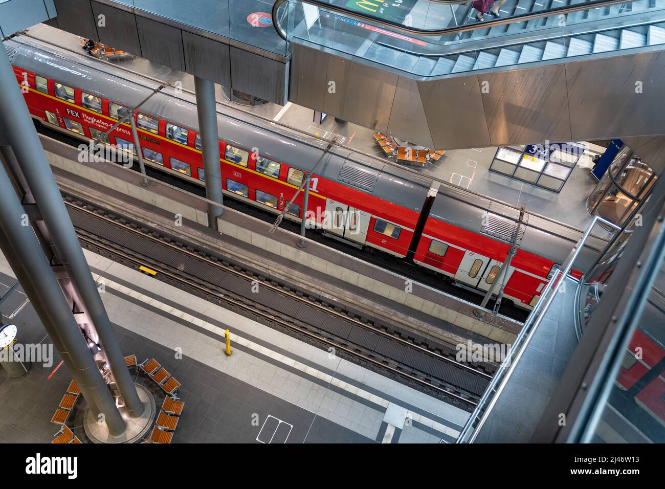 Blick auf den Hauptbahnhof von innen, wenn man auf die Bahngleise schaut. Ein roter Zug der Deutschen Bahn AG wartet auf Fahrgäste. Stockfoto