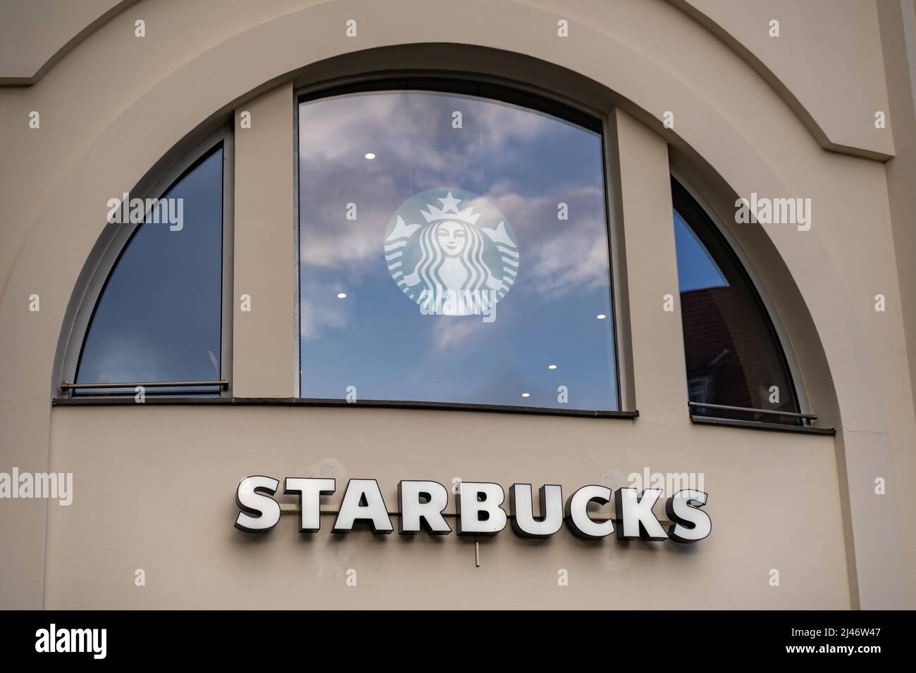 Starbucks-Buchstaben und das Logo als Teil der Fassade eines Gebäudes in der Stadt. Werbung für das berühmte Kaffeeunternehmen, das ein Franchise betreibt Stockfoto
