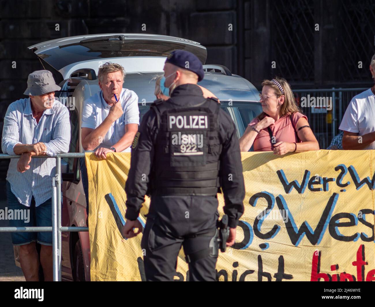 Polizist vor Querdenken-Demonstranten. Demonstration gegen die deutsche Bundeskanzlerin Angela Merkel mit Pfeifen, um viel Lärm zu machen. Stockfoto