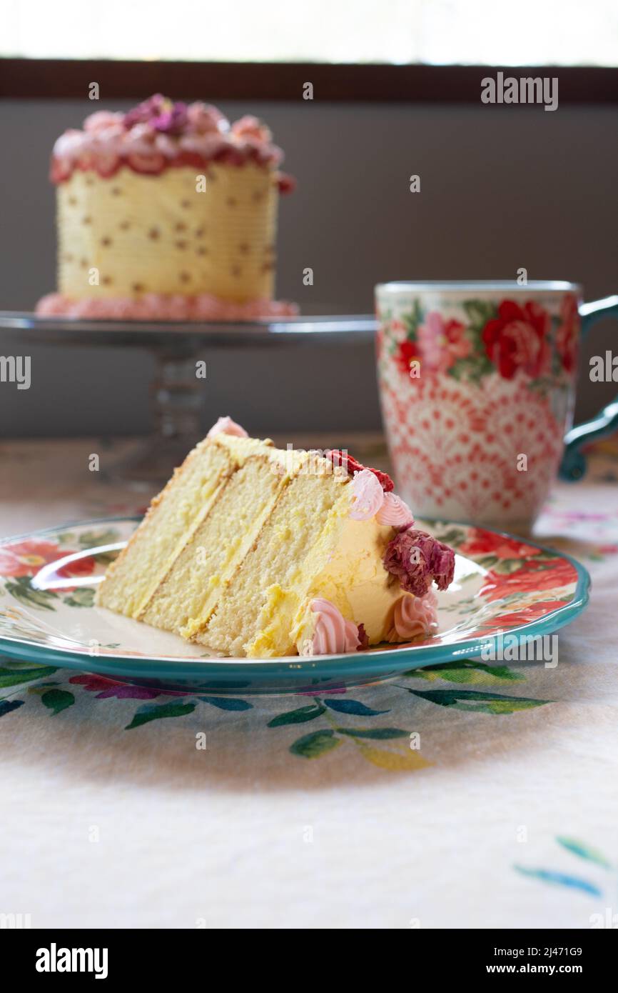 Eine Scheibe Vanillekuchen auf einem Teller, mit getrockneten Früchten und getrockneten Blumen mit einer Gabel. Stockfoto