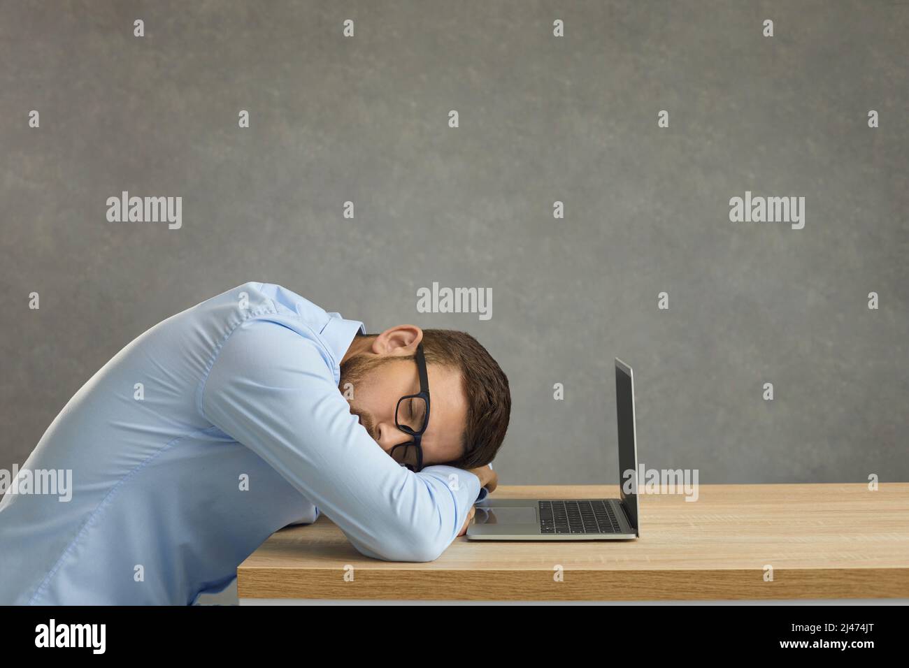 Ein müder Student oder Büroangestellter schläft am Schreibtisch in der Nähe eines Laptops Stockfoto