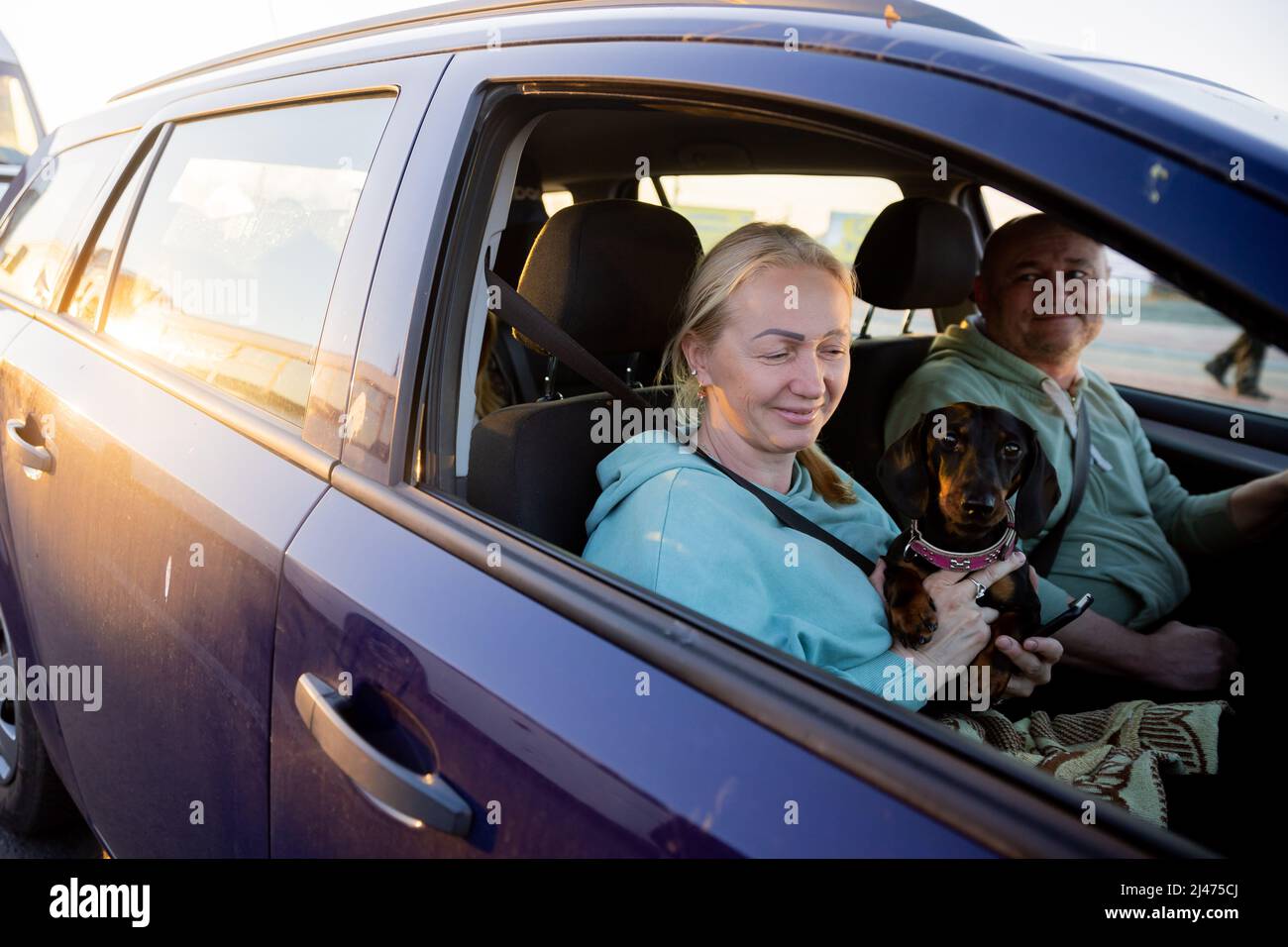 12. April 2022, Polen, Przemysl: Irina und Oleg warten mit Dackel und ihrer Tochter (nicht im Bild) auf der polnischen Seite vor dem Grenzübergang Medyka auf die Weiterreise in die Ukraine. Sie kommen aus Charkiw und wollen nun in die Ukraine zurückkehren. Als der Krieg ausbrach, floh die Familie zunächst zu Verwandten in der Nähe von Lemberg. Nach Anschlägen in der Westukraine flohen sie nach Südpolen, wo sie zweieinhalb Wochen bei Privatbürgern blieben. Jetzt wollen sie zu Verwandten in der Nähe von Lemberg zurückkehren, weil die Russen aus Charkow 'noch nicht gegangen sind'. „Natürlich wollen wir nach Hause gehen“, so der Stockfoto