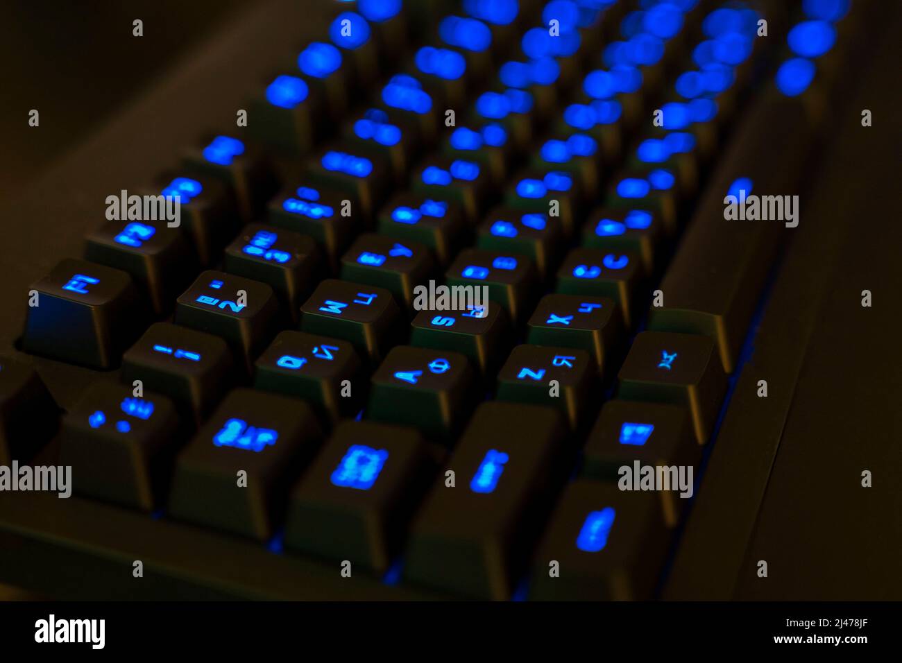 Gaming-Tastatur mit beleuchteten Tasten. Schwarze Tasten mit blau leuchtenden Buchstaben Stockfoto