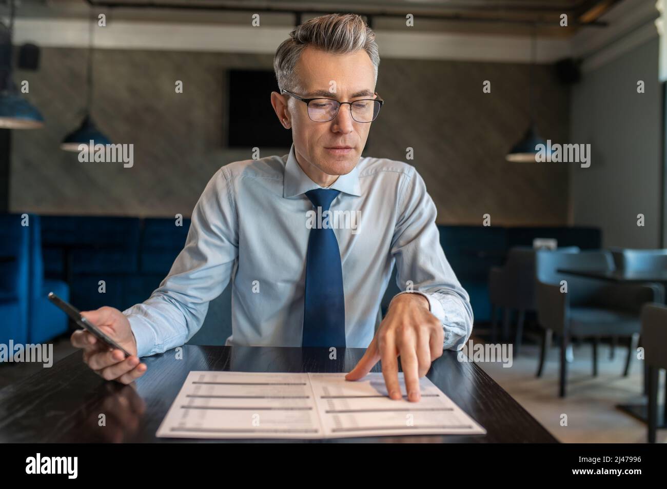 Ein eleganter Mann in einer Brille, der in einem Café sitzt Stockfoto