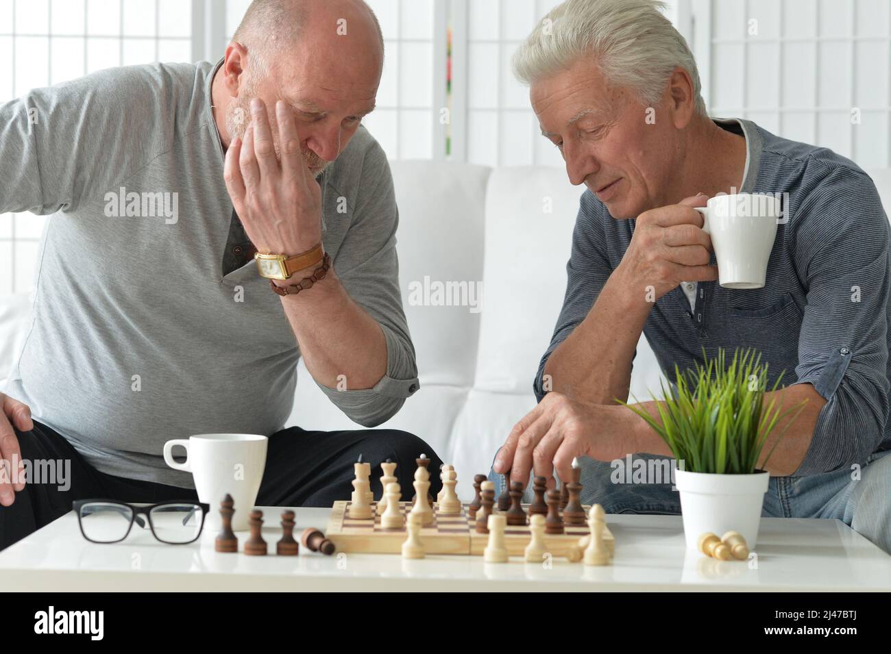 Porträt von älteren Männern, die zu Hause Schach spielen Stockfoto