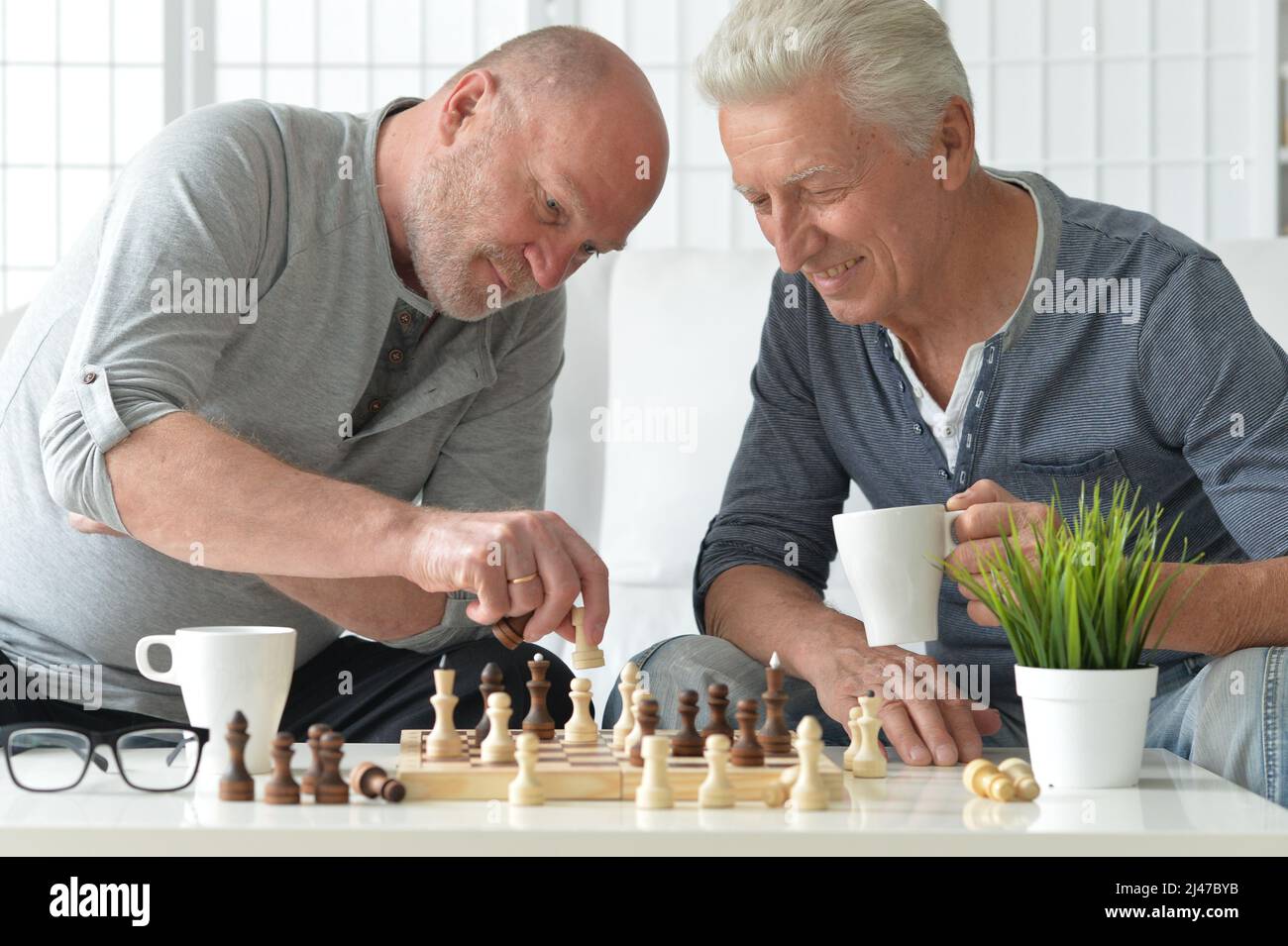Porträt von älteren Männern, die zu Hause Schach spielen Stockfoto