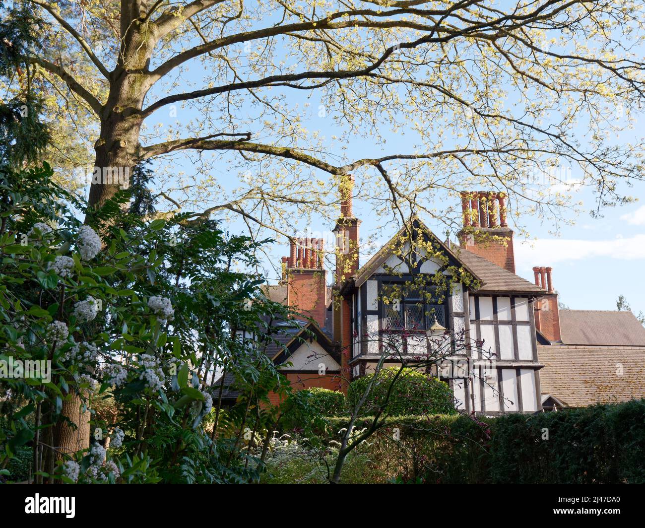 Watford, Hertfordshire, England, April 07 2022: Baum, Blumenbeete, Hecke und Bank auf dem Gelände von Bhaktivedanta Manor, einem ISKCON-Standort. Stockfoto