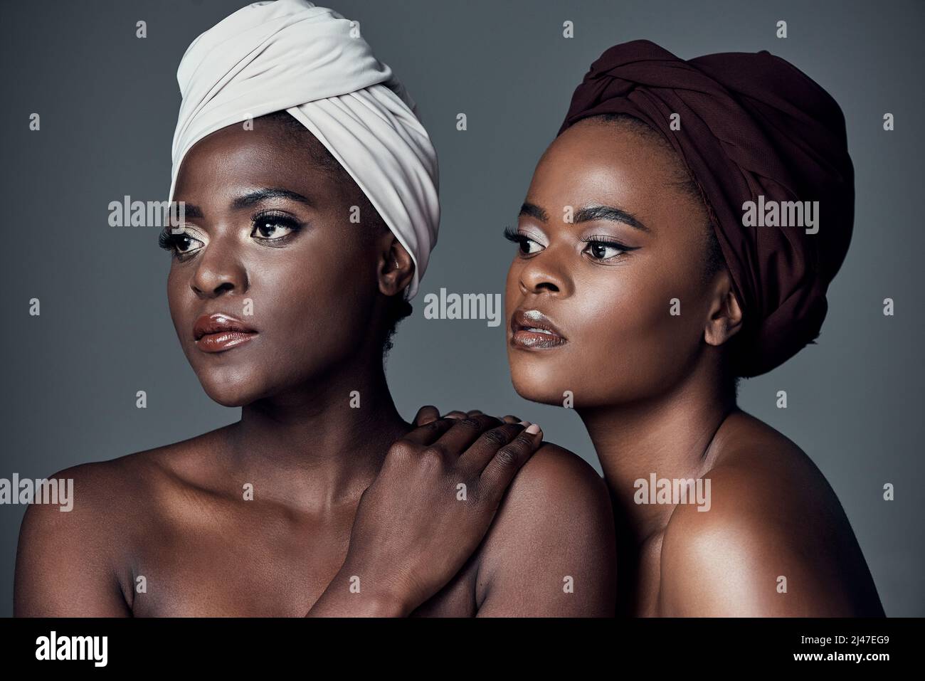 Afrikanische Königinnen. Studioaufnahme von zwei schönen jungen Frauen, die vor einem grauen Hintergrund posieren. Stockfoto