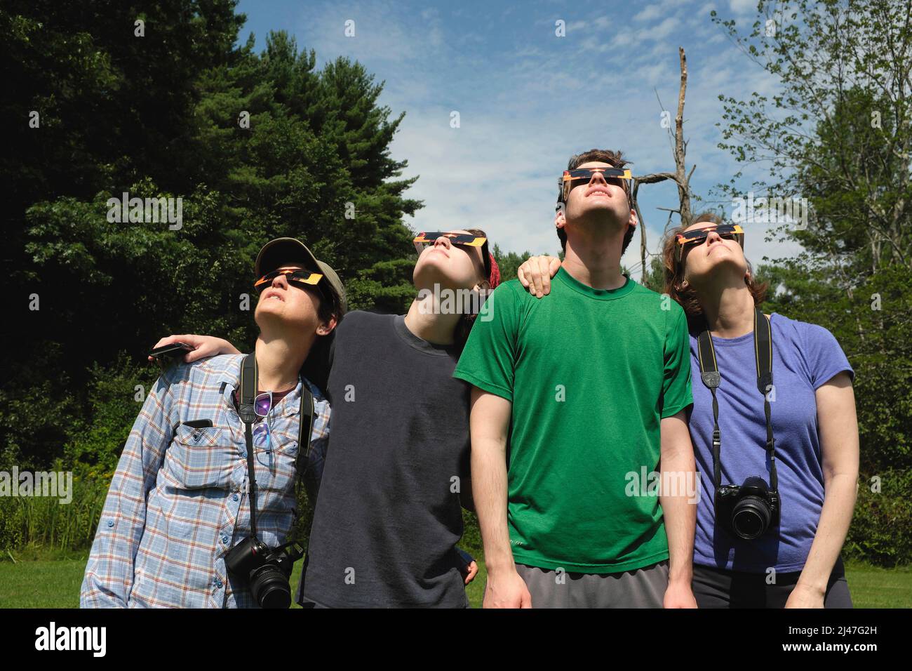 Kleine Gruppe von Menschen, die eine Eclipse-Brille tragen, während sie sich die partielle Sonnenfinsternis ansehen Stockfoto