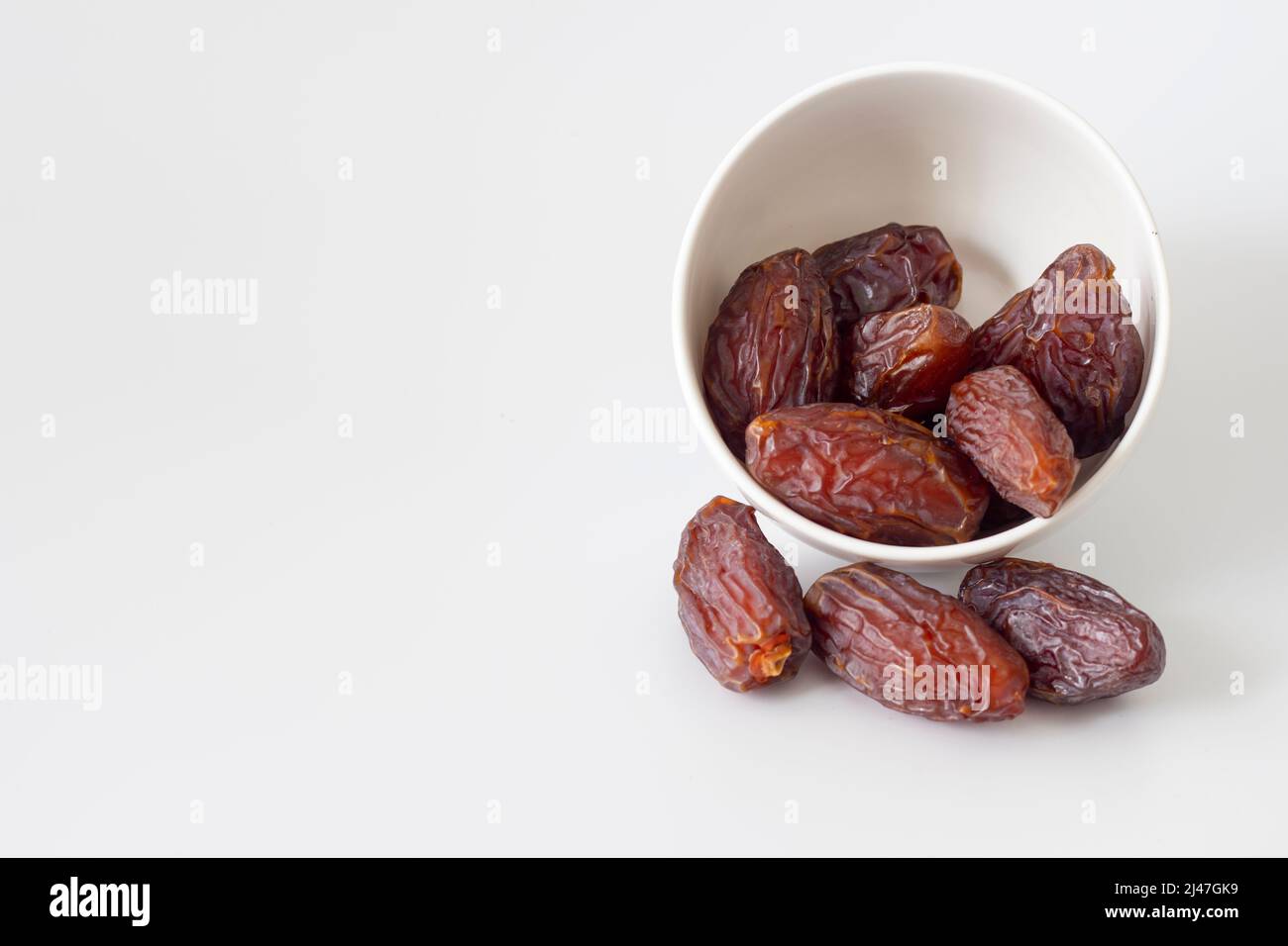 Datum Früchte verschüttet aus Schüssel isoliert auf weißem Hintergrund. Ramadan-Früchte Stockfoto