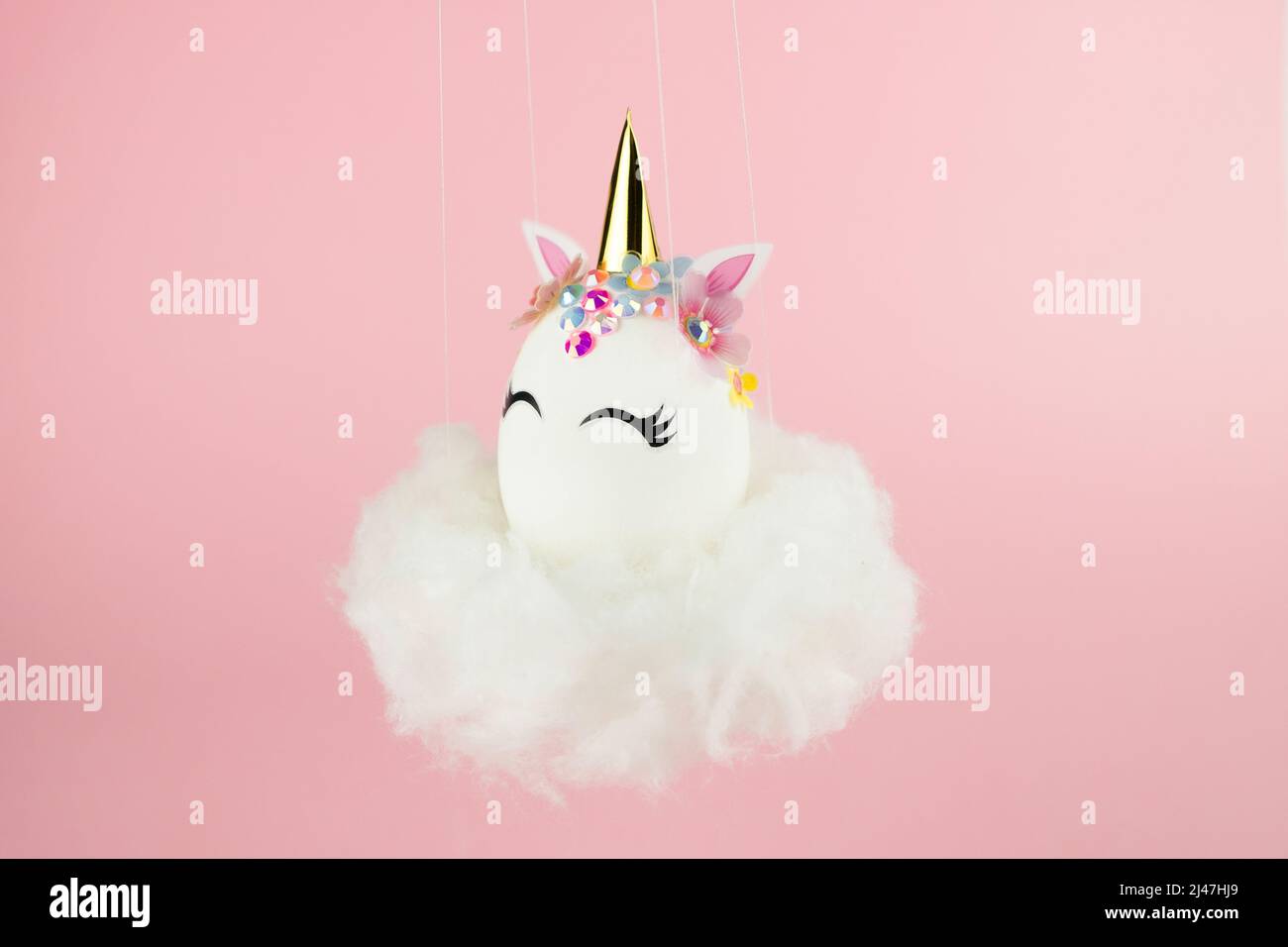 Ostereinhorn-Ei fliegt auf Wolke auf pastellrosa Hintergrund. Frohe ostern Banner. Inspiration für Aktivitäten für Kinder. Grußkarte oder Poster. Speicherplatz kopieren für Stockfoto