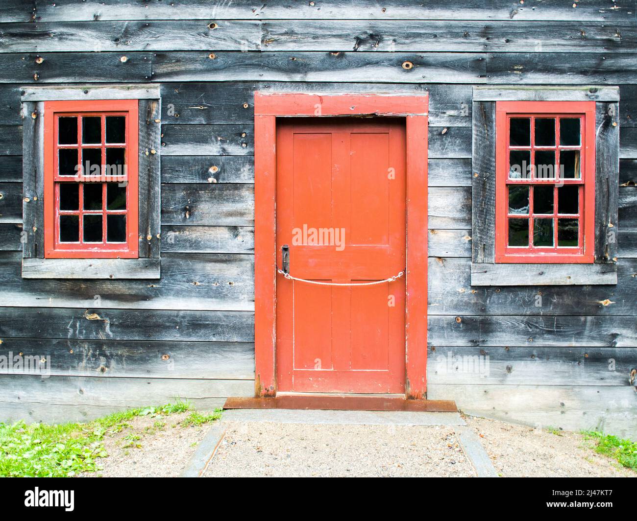 Rustikales Kolonialhaus mit roten Tür- und Fensterrahmen im Sturbridge Village Massachusetts USA Stockfoto