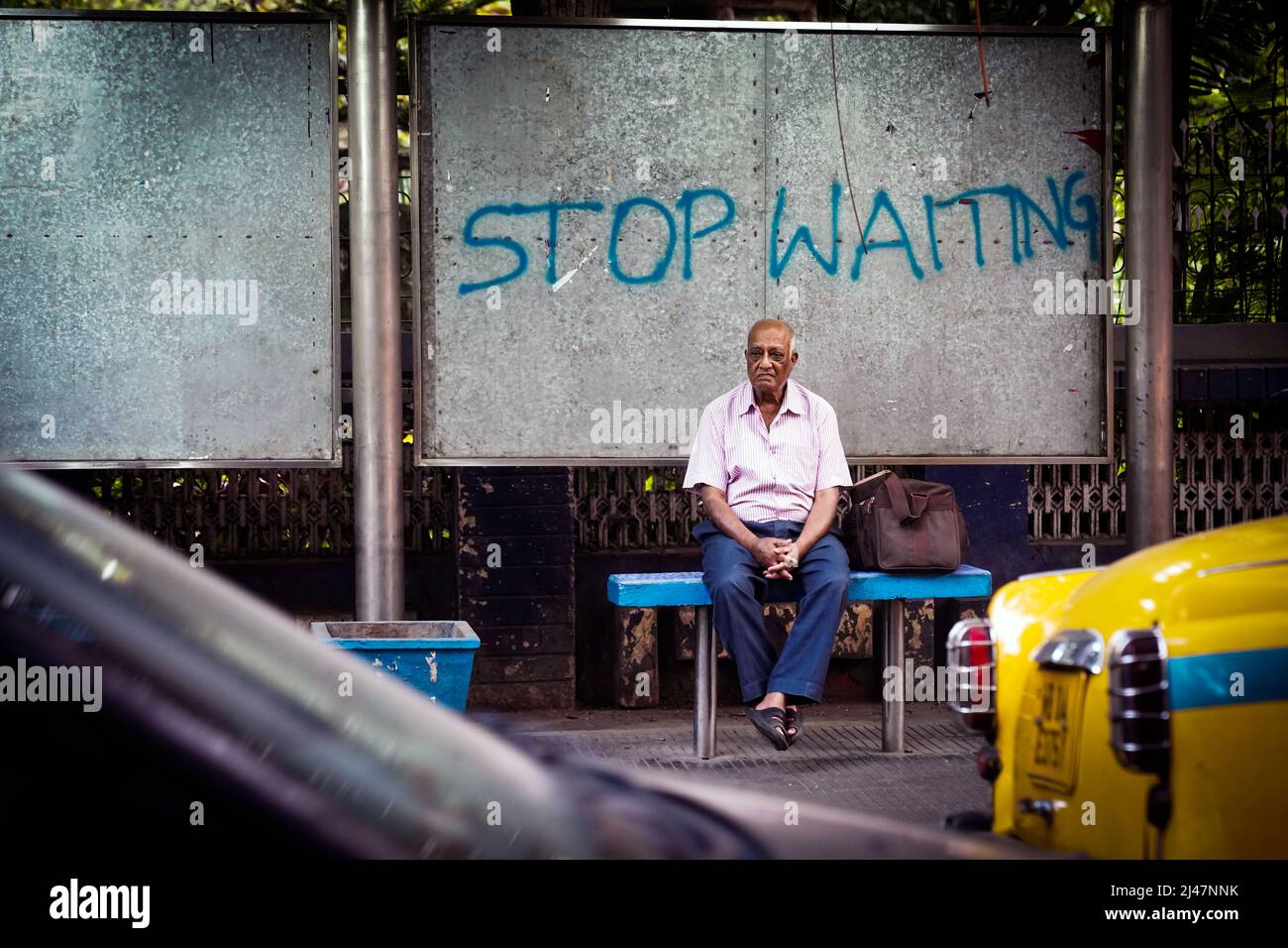Mann, der an einer Bushaltestelle in Kalkutta, Indien, sitzt und wartet Stockfoto