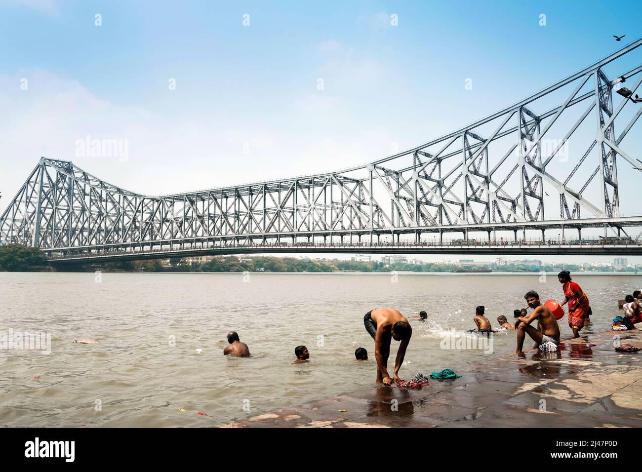 Die Menschen nehmen ein Bad im Hooghly River (Mündung des Ganges) in der Nähe der Howrah Bridge (Rabindra Setu) in Kalkata, Indien. Stockfoto