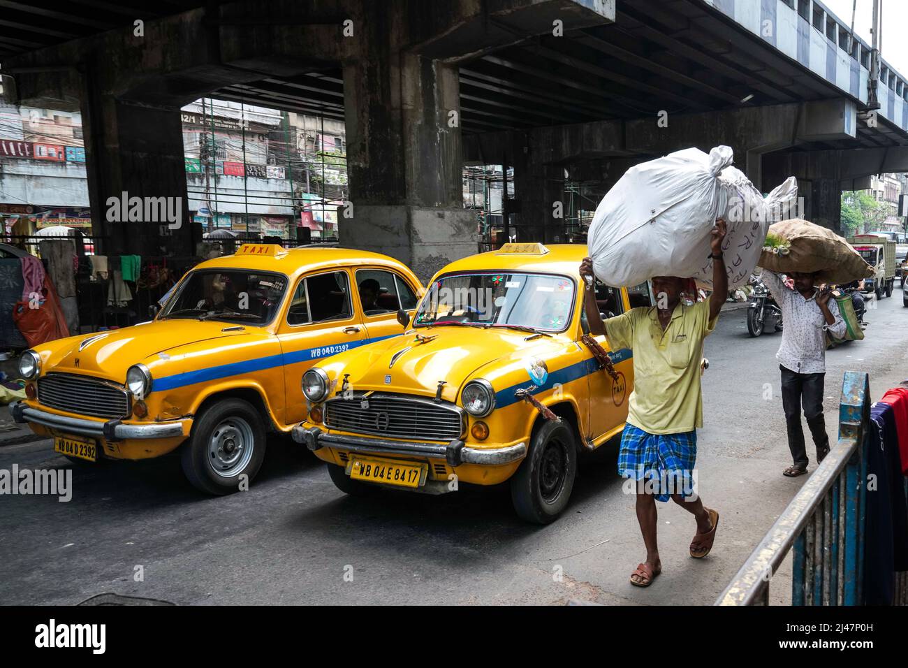 Historisches gelbes Ambassador-Taxi, Verkehr auf der Howrah-Brücke in Kalkutta, Westbengalen, Indien Stockfoto