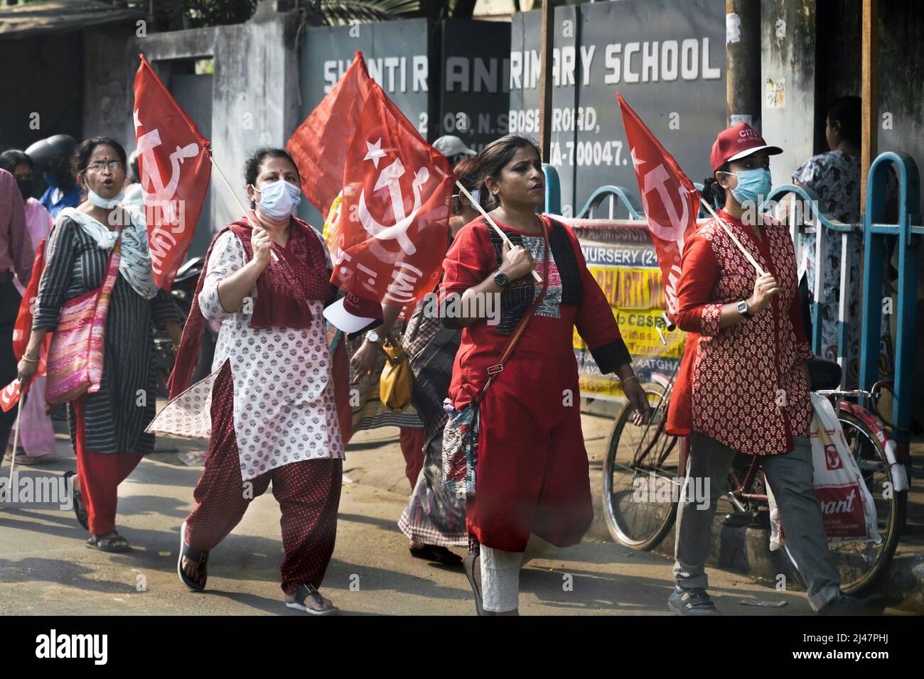 Demonstranten der kommunistischen Partei marschieren mit Hammer- und Sichelfahnen durch eine Straße in Kalkutta, Indien Stockfoto