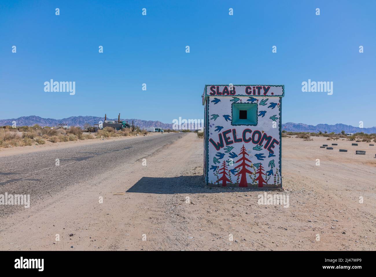 Ein winziges Gebäude mit einem Wandgemälde, das Besucher in Slab City willkommen heißt. Es ist eine netzunabhängige Gemeinde ohne kommunale Dienste. Es bekommt es nam Stockfoto