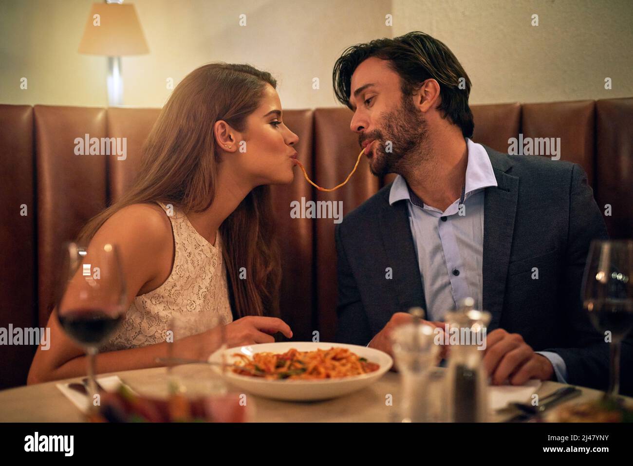 Nichts inspiriert Romantik wie italienisches Essen. Aufnahme eines jungen Paares, das während eines romantischen Abendessens in einem Restaurant Spaghetti teilt. Stockfoto