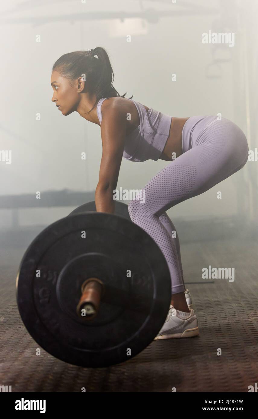 Heben Sie etwas Gewicht und ändern Sie Ihr Leben. Aufnahme einer sportlichen jungen Frau, die in einem Fitnessstudio Langhantel-Entliftungen macht. Stockfoto