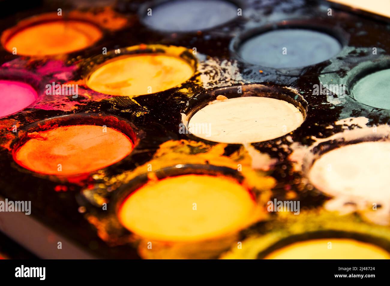 Schwarze Farben werden perspektivisch mit bunten Trockenfarben und Farbspritzern lackiert. Kunst und Handwerk Hintergründe Stockfoto