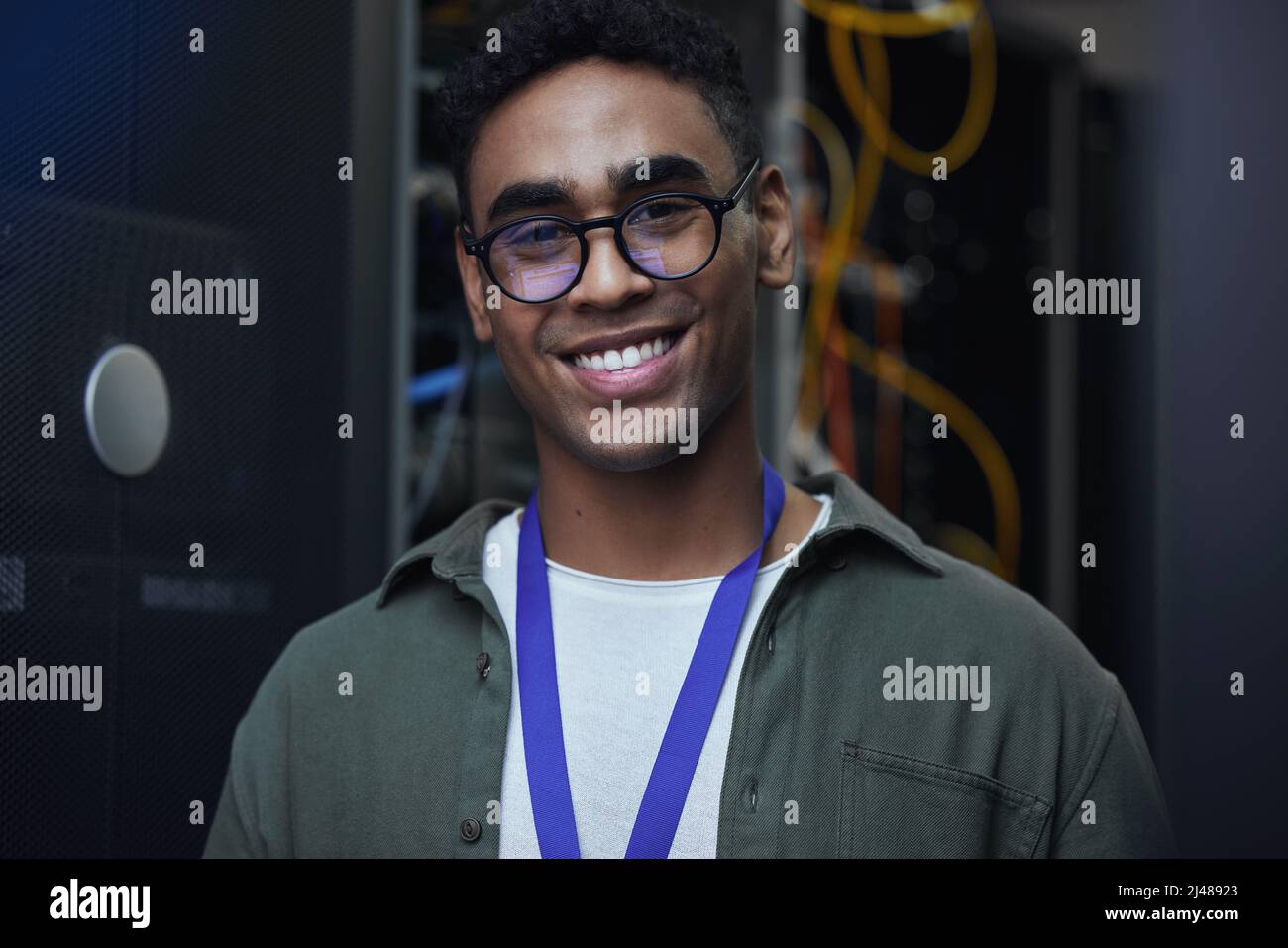 ES ist mein Spiel. Beschnittenes Porträt eines hübschen männlichen IT-Support-Agenten, der in einem dunklen Netzwerkserverraum arbeitet. Stockfoto