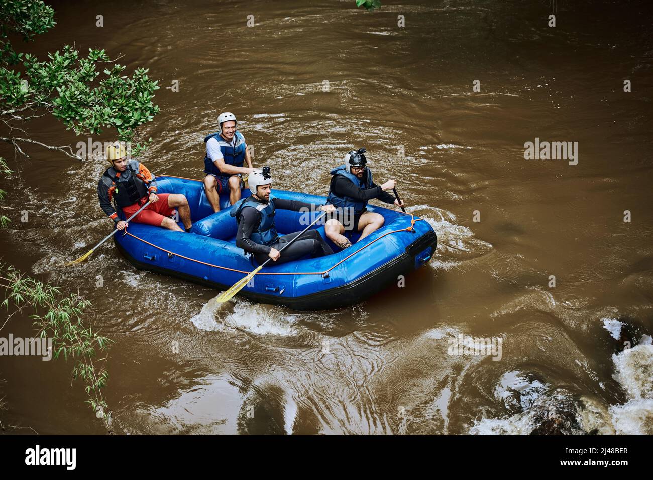 Nun, das war ziemlich extrem. Aufnahme einer Gruppe fröhlicher junger Menschen in einem Gummiboot, das tagsüber auf einem Fluss draußen paddelt. Stockfoto