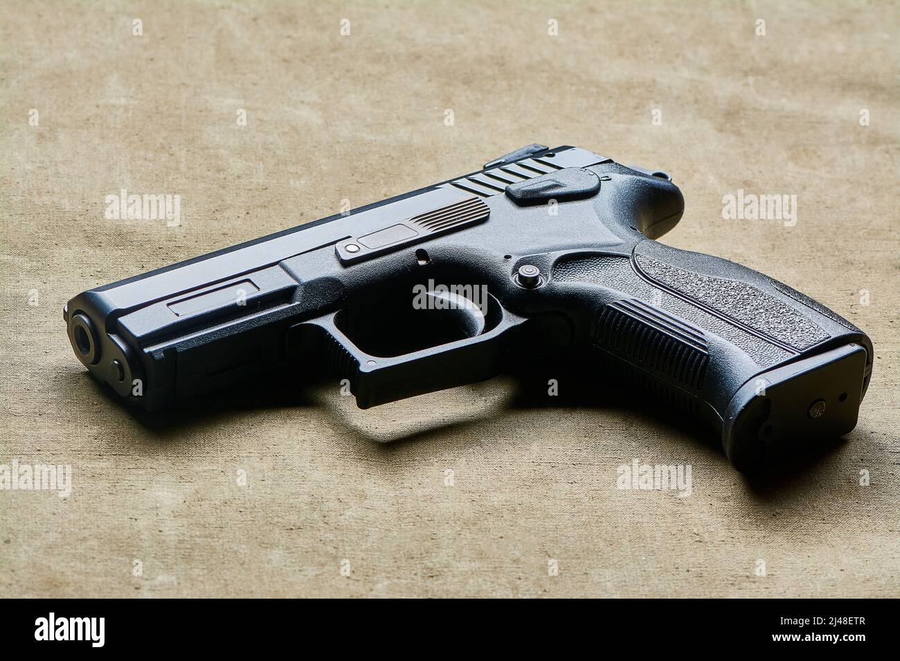 Eine schwarze Pistole in Nahaufnahme liegt auf einem Leinwandhintergrund, einer Feuerwaffe Stockfoto